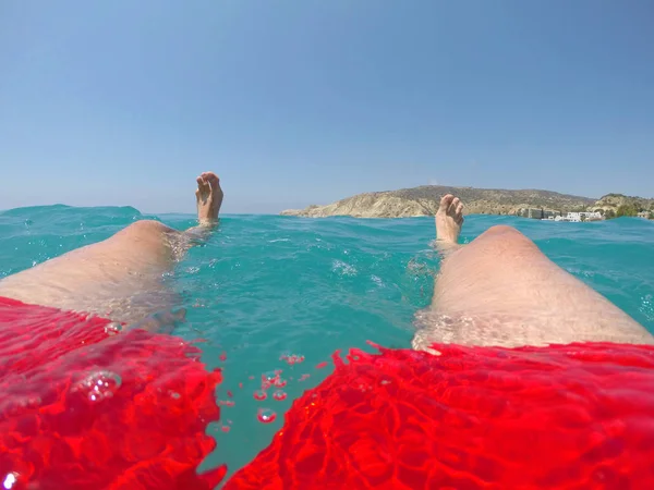 男は海の水に浮かんでいる 海に浮かぶ赤い水着の水泳の足と足 — ストック写真