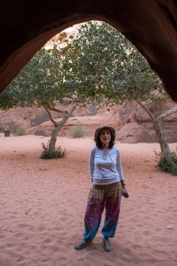 Woman posing in front of a small cave clipart