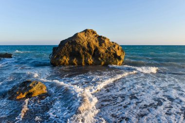 Beyaz dalgalar çökmesini karşı bir kayalık plaj