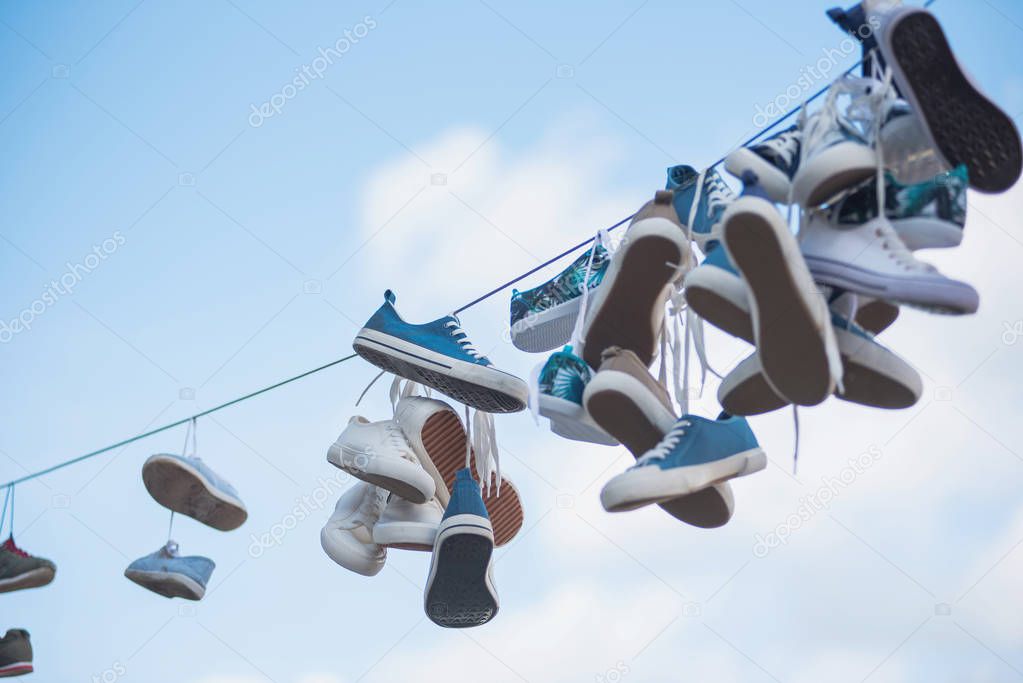 Pairs of sneakers and shoes hanging on cable