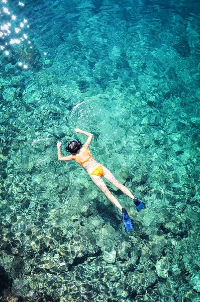 透明な青い海でシュノーケ リング オレンジ ビキニの若い女性のトップ ビュー — ストック写真