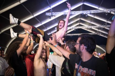 BONTIDA, ROMANIA - JULY 22, 2018: Guy doing crowd surfing, stage diving during a Cancer Bats live concert at Electric Castle festival clipart