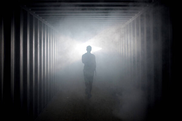 Light at the end of the tunnel. Silhouette of person in underground corridor
