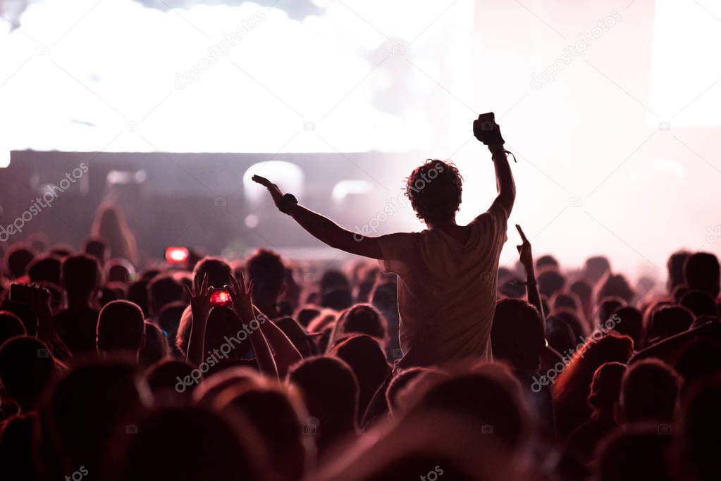 Rock concert, silhouette of people raising up hands