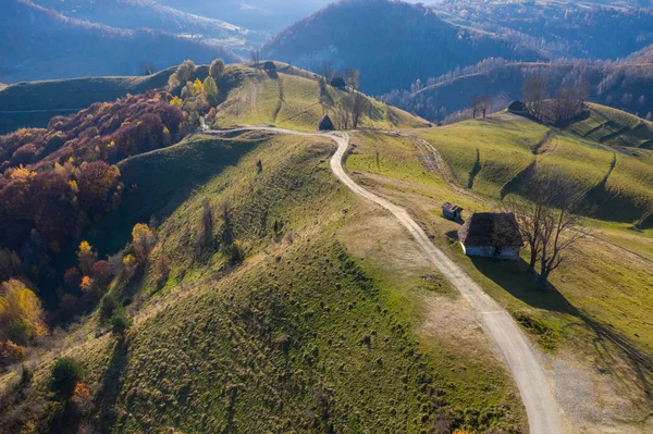 茅葺き ルーマニア トランシルバニアの未舗装の道路と秋の田園地帯山の風景の空中ドローン シーン — ストック写真