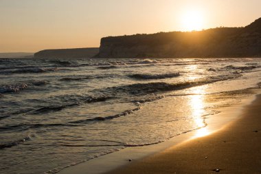 Altın gün batımında kumsala yaklaşan dalgalar