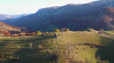 Sonbahar kırsal dağ manzarası ile ahşap evler, thatched çatı ve toprak yola Transilvanya, Romanya hava dron 4k görünümü