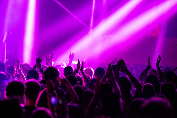 Audience, crowd with hands raised partying at a music festival. Stage lights