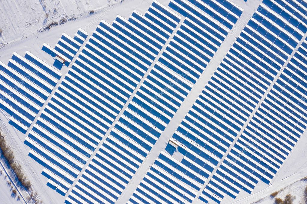 Aerial drone view of snow covered solar panel park, photovoltaic power station in the winter