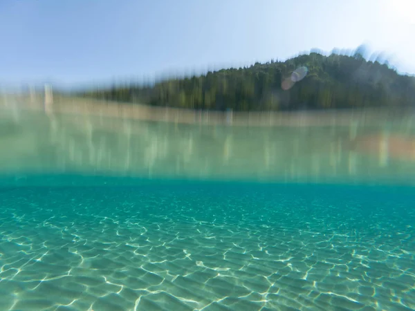 Polovina Podvodní Záběr Zrušte Tyrkysovou Mořskou Vodou Rozmazaný Ostrov — Stock fotografie