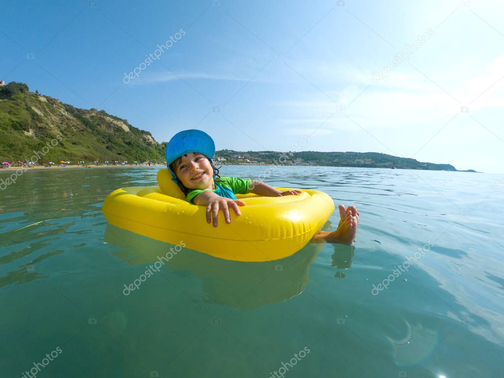 Adorable baby girl swimming in the sea in a rubber ring