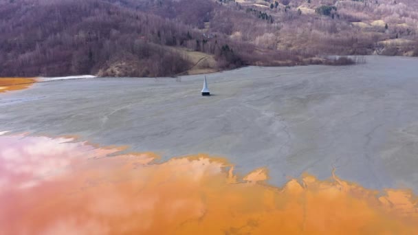 化学廃棄物の上空を飛んで 汚染された鉱業で水を汚染した銅鉱山からの残余は 湖に混合する有毒なシアン化液体の下に埋もれていた教会を放棄した 空中ドローンビュー 生態学的大惨事 — ストック動画