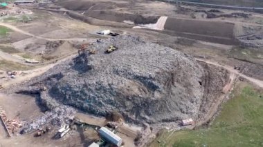 Büyük çöp yığını hava üst drone görünümü, çöp dökümü, atık depolama, ev atıcı site çöp, ekskavatör makinesi bir dağ çöp üzerinde çalışıyor. Tüketim ve kontaminasyon konsepti