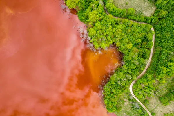 Aerial view of red waste water and green forest — Stock Photo, Image