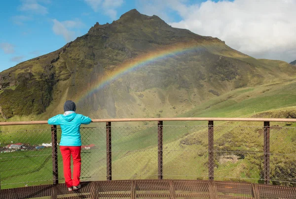 Donna che ammira l'arcobaleno sulla cascata Skogafoss in Islanda — Foto Stock