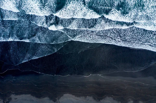 Vista aérea del dron de las olas del océano lavando la playa de arena negra, Islandia —  Fotos de Stock