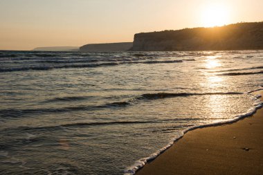 Gün batımı sırasında kumsala yaklaşırken dalgalar