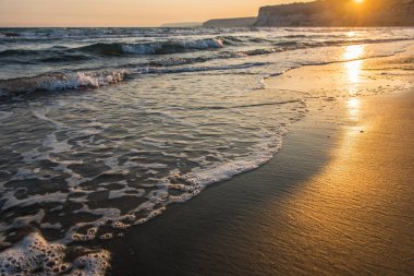 Gün batımı sırasında kumsala yaklaşırken dalgalar