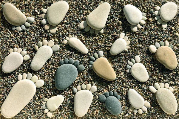 Footprints z kamieni żwirowych na piasku plaży — Zdjęcie stockowe