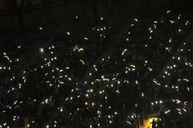 Karanlık bir tribünde parlayan akıllı telefonların hareket bulanıklığı