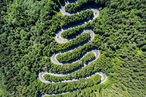 Letecký vrcholní pohled na klikatící se silnici v zeleném lese — Stock fotografie