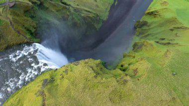  İzlanda 'daki Skogafoss şelalesinin üzerinde uçan 4k hava aracı görüntüsü. Canlı yeşil İzlanda manzarası 