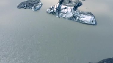 İzlanda 'daki eriyen Solheimajokull buzulunun 4k hava aracı yüksek açılı görüntüsü. İklim değişikliği, eriyen buzullar, küresel ısınma kavramı