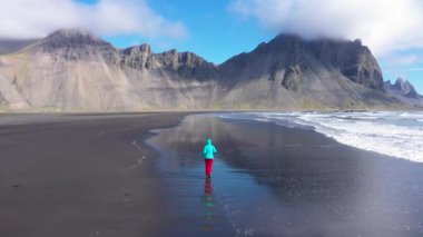 Atlantik Okyanusu kıyısında koşan bir kadın. Stokssnes, Vestrahorn Dağları, Hofn, İzlanda