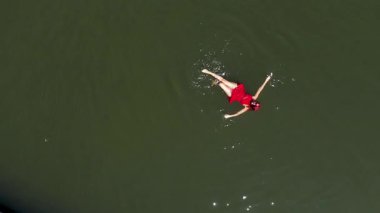 Suda yüzen kırmızı elbiseli bir kadın.