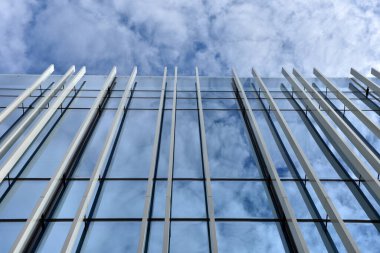 Gökdelen penceresi mavi gökyüzüne bakıyor, bulutlar pencerelere yansıyor