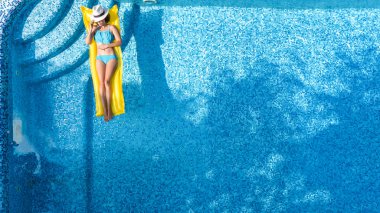 Güzel genç kız rahatlatıcı yüzme havuzunda şişme yatak üzerinde yüzüyor ve aile tatil tropikal tatil, hava uçak görünümü yukarıdan su eğlence var