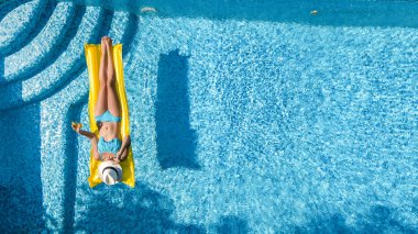 Güzel genç kız rahatlatıcı yüzme havuzunda şişme yatak üzerinde yüzüyor ve aile tatil tropikal tatil, hava uçak görünümü yukarıdan su eğlence var