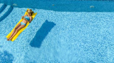 Güzel genç kız rahatlatıcı yüzme havuzunda şişme yatak üzerinde yüzüyor ve aile tatil tropikal tatil, hava uçak görünümü yukarıdan su eğlence var
