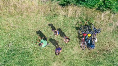 Bisikletle gezen aile, bisiklete binen aktif ebeveynler ve çocuklar, yukarıdan güzel nehrin yanında dinlenen çocuklar, spor ve fitness konsepti.