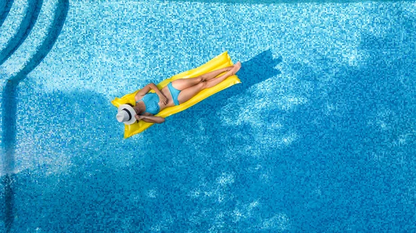 スイミング プールでリラックスした美しい若い女の子の膨脹可能なマットレスの上を泳ぐし 水の楽しみは 家族での休暇 熱帯リゾート地で上から空中ドローン ビュー — ストック写真