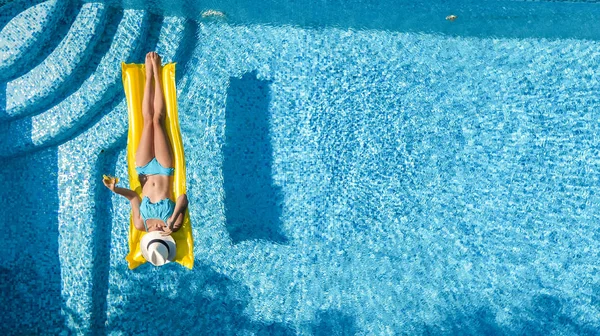 Güzel genç kız rahatlatıcı yüzme havuzunda şişme yatak üzerinde yüzüyor ve aile tatil tropikal tatil, hava uçak görünümü yukarıdan su eğlence var