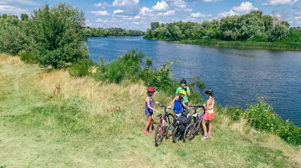 屋外での自転車サイクリング 自転車での積極的な親と子供 美しい川の近くでリラックスした子供たちと幸せな家族の空中ビュー スポーツとフィットネスのコンセプト — ストック写真