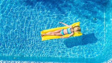 Güzel genç kız rahatlatıcı yüzme havuzunda şişme yatak üzerinde yüzüyor ve aile tatil tropikal tatil, hava uçak görünümü yukarıdan su eğlence var