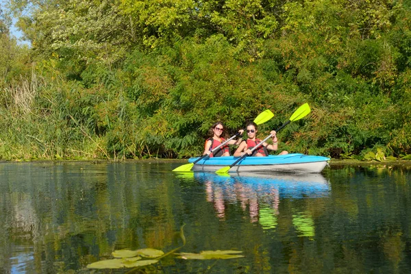 Family kayaking, mother and daughter paddling in kayak on river canoe tour having fun, active autumn weekend and vacation with children, fitness concept