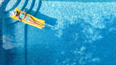 Güzel genç kız rahatlatıcı yüzme havuzunda şişme yatak üzerinde yüzüyor ve aile tatil tropikal tatil, hava uçak görünümü yukarıdan su eğlence var