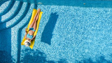 Güzel genç kız rahatlatıcı yüzme havuzunda şişme yatak üzerinde yüzüyor ve aile tatil tropikal tatil, hava uçak görünümü yukarıdan su eğlence var