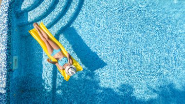 Güzel genç kız rahatlatıcı yüzme havuzunda şişme yatak üzerinde yüzüyor ve aile tatil tropikal tatil, hava uçak görünümü yukarıdan su eğlence var
