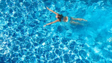 Yüzme havuzundaki aktif kız yukarıdan drone görüntüsü, mavi suda yüzen genç kadın, tropikal tatil, tatil konseptinde tatil