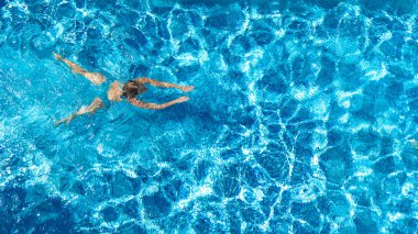 Yüzme havuzundaki aktif kız yukarıdan drone görüntüsü, mavi suda yüzen genç kadın, tropikal tatil, tatil konseptinde tatil