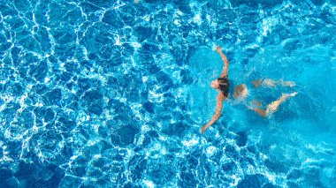 Yüzme havuzundaki aktif kız yukarıdan drone görüntüsü, mavi suda yüzen genç kadın, tropikal tatil, tatil konseptinde tatil