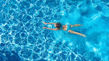 Yüzme havuzundaki aktif kız yukarıdan drone görüntüsü, mavi suda yüzen genç kadın, tropikal tatil, tatil konseptinde tatil