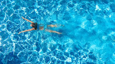 Yüzme havuzundaki aktif kız yukarıdan drone görüntüsü, mavi suda yüzen genç kadın, tropikal tatil, tatil konseptinde tatil