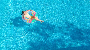 Hava dron görünümünü yüzme havuzundan yukarıdaki küçük kız, çocuğu şişme halka çörek üzerinde yüzüyor, çocuğu olan aile tatil tatil su eğlenceli mavi