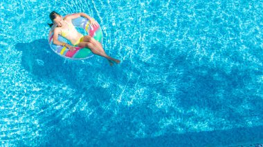 Hava dron görünümünü yüzme havuzundan yukarıdaki küçük kız, çocuğu şişme halka çörek üzerinde yüzüyor, çocuğu olan aile tatil tatil su eğlenceli mavi