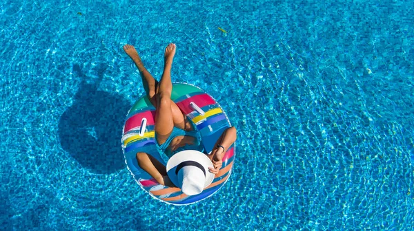Yüzme Havuzu hava dron görünümünde yukarıdan şapkalı güzel kız, kadın rahatlatır ve şişme üzerinde yüzer halka halka ve eğlenir suda Ailecek tatile tropikal tatil